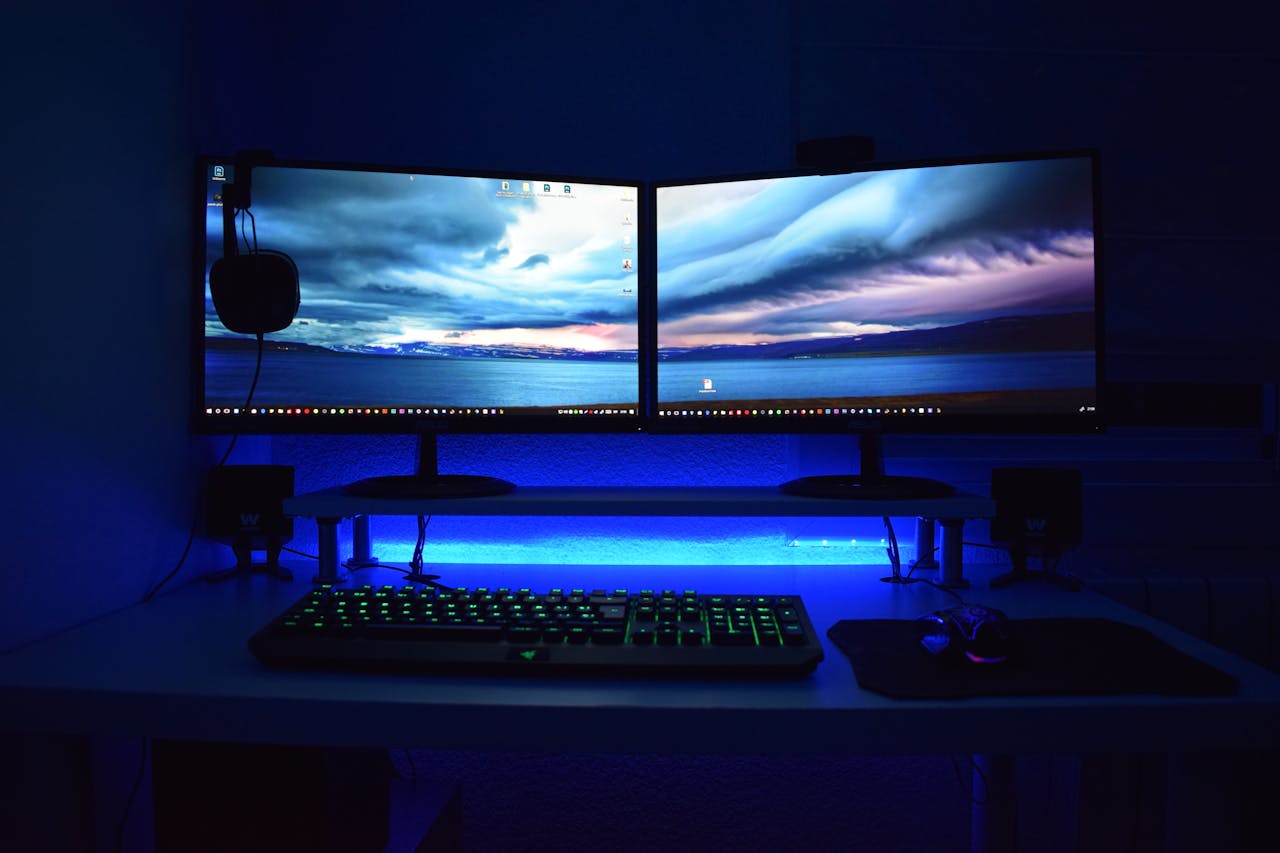why-choose-us Dual monitors with blue lighting on a gaming desk setup.